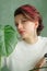 Portrait of a young beautiful woman with perfect smooth skin with a large green tropical leaf. Fashion, beauty, makeup