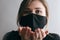Portrait of young beautiful woman in protective black stylish mask sending air kiss, quarantine limitations and epidemic