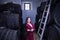 Portrait of young and beautiful woman in a red dress next to a ladder to check the wine barrels in her cellar with a wine pourer