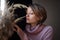 Portrait of a young beautiful woman touching wheat spikelets. Blonde girl wearing pink sweater in scandinavian interior