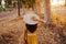 Portrait of young beautiful woman wearing a yellow dress walking by a path of trees. Summertime and lifestyle. Back view