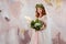 Portrait of a young beautiful woman in wedding dress with wreath and bouquet of fresh flowers.