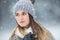 Portrait of young beautiful woman in winter clothes and strong snowing