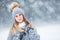 Portrait of young beautiful woman in winter clothes and strong snowing