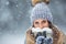 Portrait of young beautiful woman in winter clothes and strong snowing