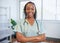 Portrait of a young Black female doctor, arms folded smiling in moden office