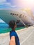 Portrait of a young black male tourist in front of a cruise ship on cloudy sky. African tourist on the beach trip