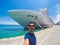 Portrait of a young black male tourist in front of a cruise ship on cloudy sky. African tourist on the beach trip