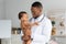 Portrait Of Young Black Pediatrician Holding Adorable Little Infant Boy In Hands