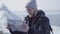 Portrait of young blond bearded handsome man in warm jacket and hat standing on the glacier checking with the map