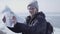 Portrait of young blond bearded handsome man wearing warm jacket and hat standing on the glacier checking with the map