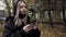 Portrait of a young blond girl typing on her smartphone device outdoors in autumn weather. Action. Beautiful teenager