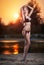 Portrait of young blonde girl in bikini posing provocatively at the beach in sunset. Sensual attractive woman in swimsuit