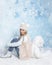 Portrait of a young blonde with long hair in winter clothes sitting with her back to a large soft polar bear . Christmas