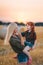 Portrait of young blonde mother and litlle red-heired daughter are in a wheat field at sunset