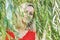 Portrait of a young blonde woman in the foliage of a weeping willow. summer time vacation
