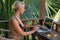 Portrait of young blonde woman freelancer working with laptop on balcony of tropical bungalow with palm trees view