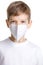 Portrait of young boy in medical mask making angry face over white