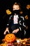 Portrait young boy wears face mask, costume dressed as halloween cosplay of scary dacula want to touch a jack`o pumpkin