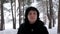 Portrait of a young brunette in a fur coat, walks in snowy woods or the Park on a cold day and looking at the camera