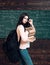 Portrait of young brunette student with heap of books and heavy rucksack holding her glasses