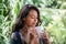 Portrait of young brunette woman freelancer drinking coffee from white cup on balcony of tropical bungalow with palm trees view