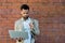 Portrait of young business man outside office building in the alley with brick wall background standing and thinking of solving