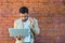 Portrait of young business man outside office building in the alley with brick wall background standing and thinking of solving