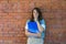 Portrait of young business woman outside office building in the alley with brick wall background standing and thinking of solving