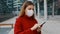 Portrait of young business woman in protective mask disinfecting cleaning her smartphone with alcohol wet wipe outdoor