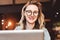 Portrait of young business woman in trendy glasses sitting in cafe,working on laptop.Blogger communicates with followers