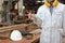 Portrait of young carpenter in white safety uniform holding a pencil in hands in wood workshop background. Industrial concept.