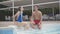 Portrait of young Caucasian couple sitting at poolside and talking. Positive handsome man and beautiful woman chatting