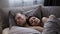 Portrait of young caucasian couple sleeping in the bed at home on the grey bed sheets. Morning time