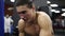 Portrait of young caucasian determined man waving battle ropes during high-intensity training indoors in the boxing gym