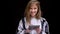 Portrait of young caucasian long-haired girl in shirt working with tablet and smiling into camera on black background.