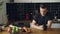 Portrait of young caucasian man sitting at table in modern spacious kitchen, looking through window, drinking tea, he is