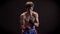 Portrait of a young caucasian topless male boxer, boxing, fight with shadow, training, black background 50 fps