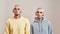 Portrait of young caucasian twin brothers with tattoos and piercings looking at camera while posing together in studio