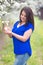 Portrait of young Caucasian woman with long dark hair, brunette, near blossoming plum tree, holding blossoming branch in hands. Lo