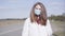 Portrait of young Caucasian woman in protective face mask standing on empty suburban road. Beautiful brunette girl