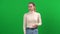 Portrait of young Caucasian woman smelling unpleasant smell on green screen. Slim beautiful lady making dissatisfied