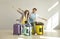 Portrait of young cheerful couple travelers flying like plane sitting on luggage