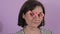 Portrait of a young cheerful woman putting on a carnival paper mask of heart-shaped glasses slow motion