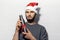 Portrait of young confidence man, wearing santa hat, holding reusable, steel thermo bottle for water with red bow for Christmas pr