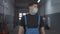 Portrait of young confident man in Covid face mask and uniform walking in repair shop looking around. Handsome Caucasian