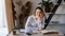 Portrait of a young consultant girl sitting at a wooden table with books and textbooks in the office by the window. A