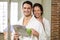 Portrait of young couple in bathrobe having tea and reading newspaper