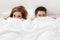 Portrait of young couple hiding face with blanket