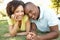 Portrait Of Young Couple Laying On Grass In Park